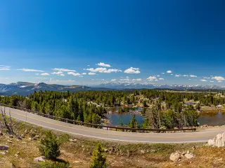 Stunning views over Beartooth Highway, with panoramic views of winding road in forefront and lush landscape and hills behind 
