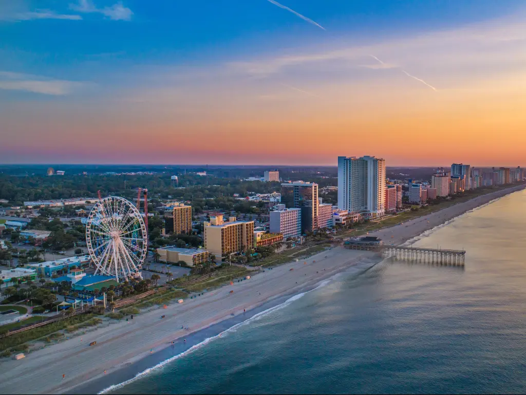 Myrtle Beach, South Carolina, USA with a view of downtown Myrtle Beach with the sea and skyline in the distance at sunset.