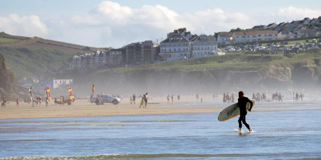 Surfer runs across a beach in Cornwall