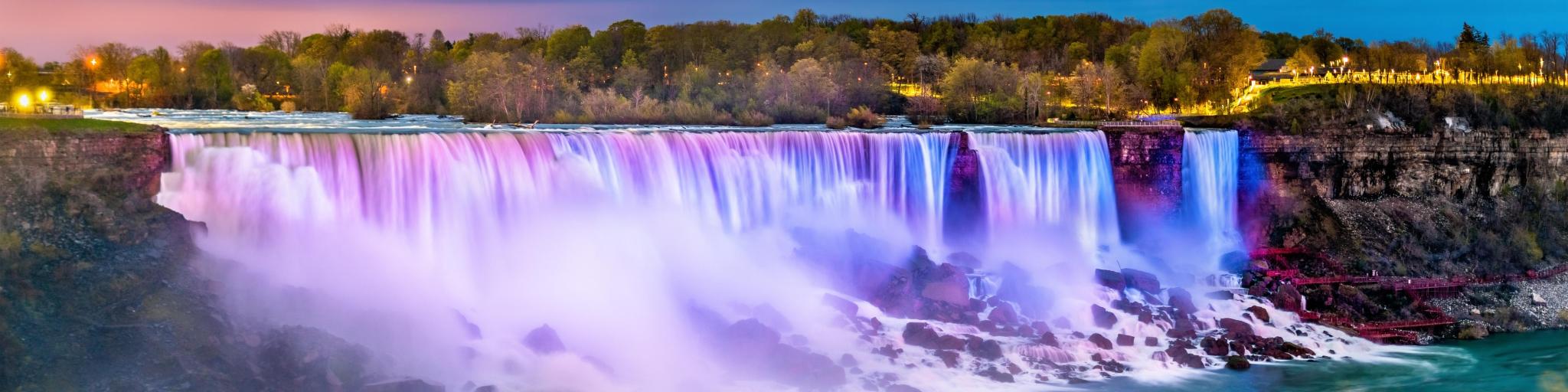 Niagara Falls, Canada with the American Falls and the Bridal Veil Falls in the foreground taken from the Canadian side at night with the waterfall reflected in colors of pinks, blues and purples. 
