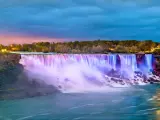Niagara Falls, Canada with the American Falls and the Bridal Veil Falls in the foreground taken from the Canadian side at night with the waterfall reflected in colors of pinks, blues and purples. 