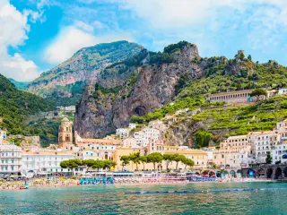 Panoramic view, aerial skyline of small haven of Amalfi village with tiny beach and colorful houses located on rock. 