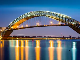 Bayonne Bridge at dusk. The Bayonne Bridge, is the 5th longest steel arch bridge in the world, spans the Kill Van Kull and connects Bayonne, NJ with Staten Island, NY