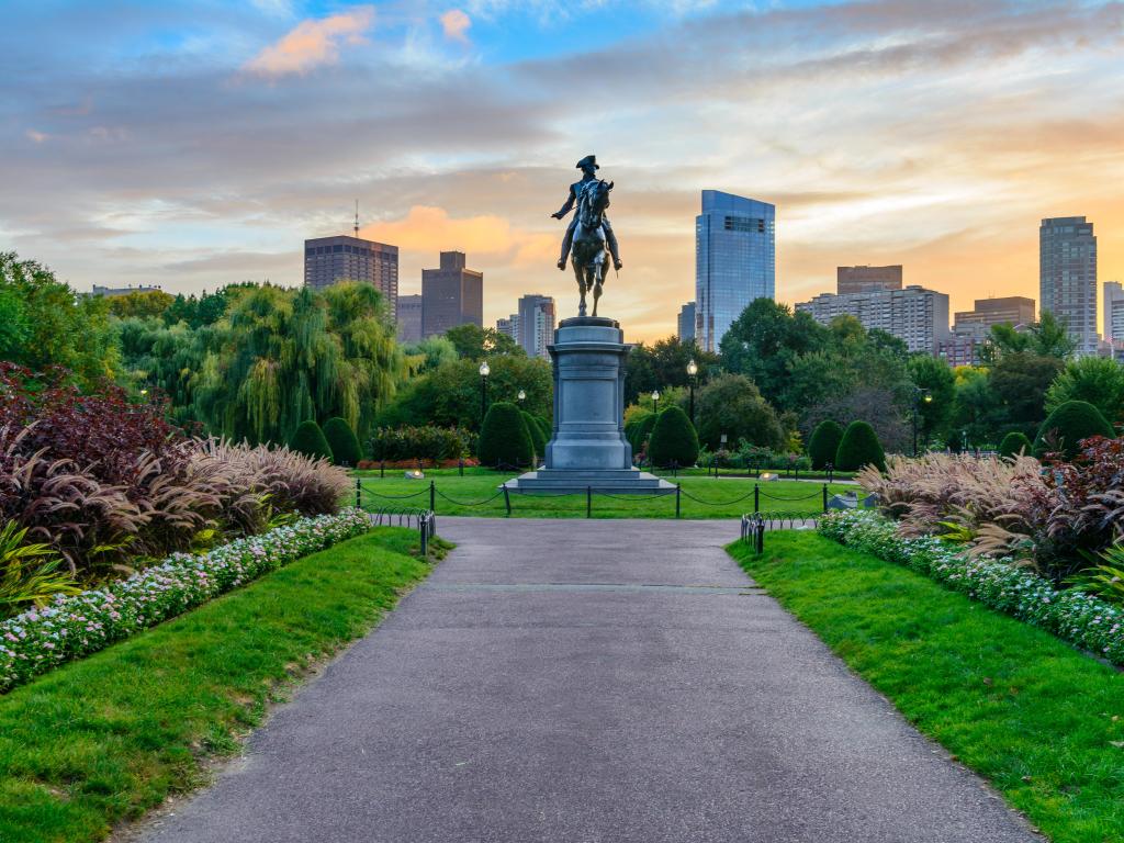 Boston Public Garden, Boston, USA with the Washington statue in Boston Public Garden and the skyline in the distance taken at sunset.