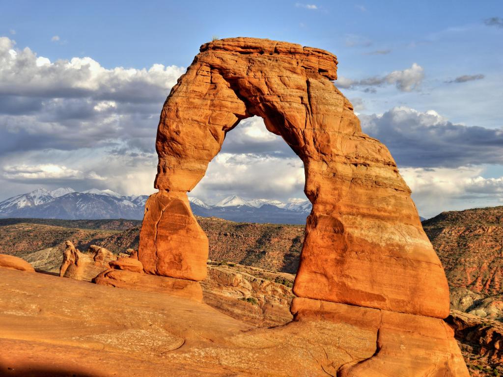 Arches National Park, Moab, Utah, USA with the delicate arch in the foreground and the mountains in the distance taken on a sunny day.