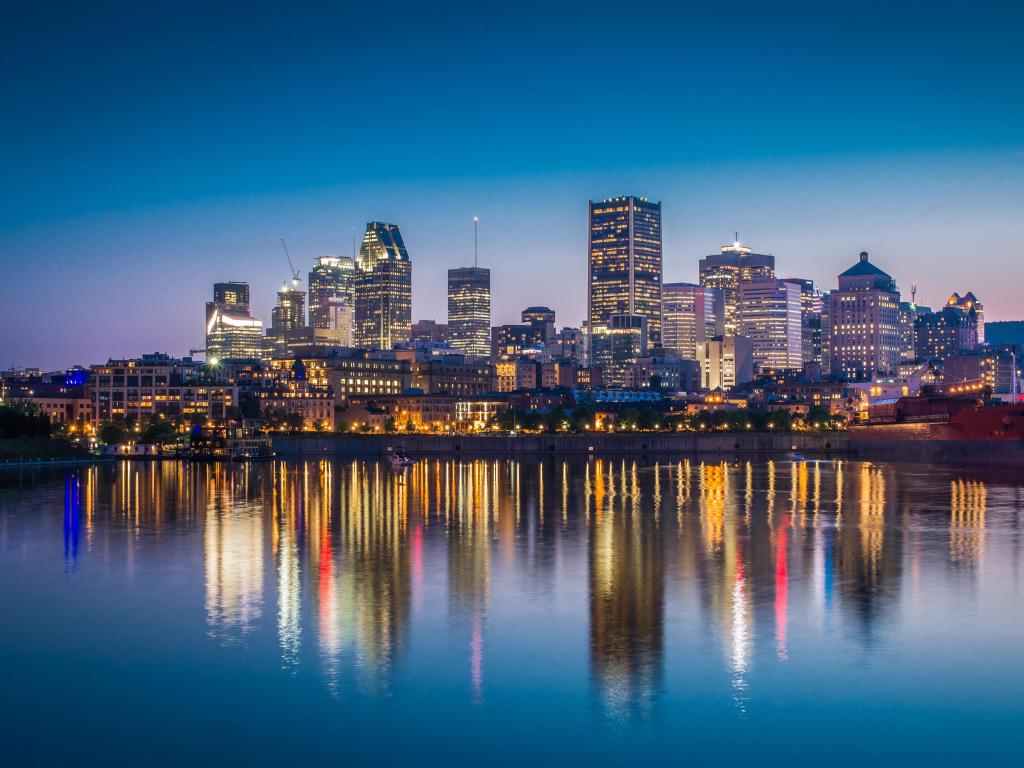 Montreal, Quebec, Canada with a view of the city downtown from across St Lawrence River at night with the city reflecting in the water below.