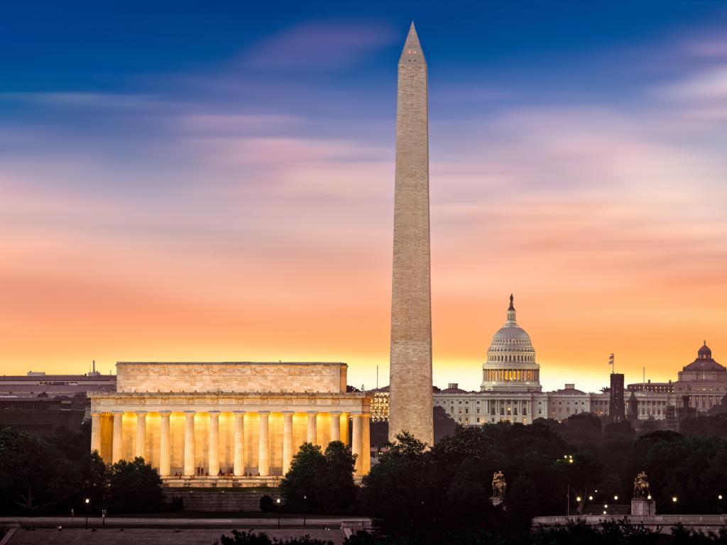 Washington, DC, USA taken at dawn over Washington with three iconic monuments illuminated at sunrise: Lincoln Memorial, Washington Monument and the Capitol Building.