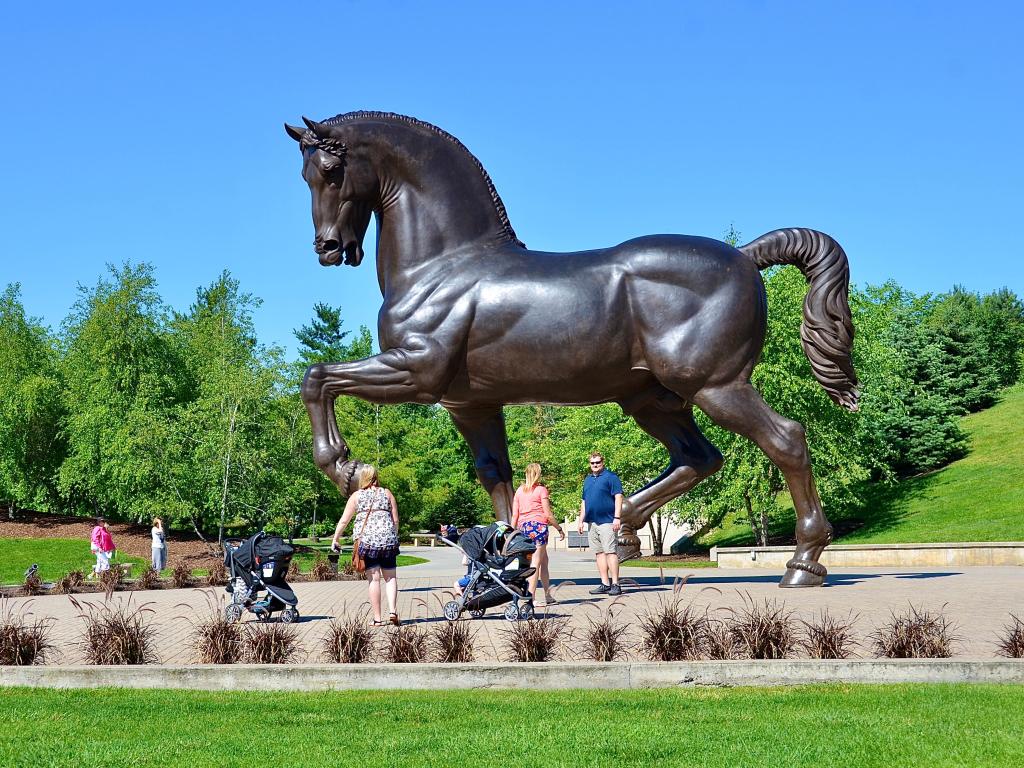 Big bronze horse statue at the park with families walking around it