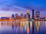 Lit-up skyline of Louisville after the sun has set, purple sky with the reflection of the buldings in the water