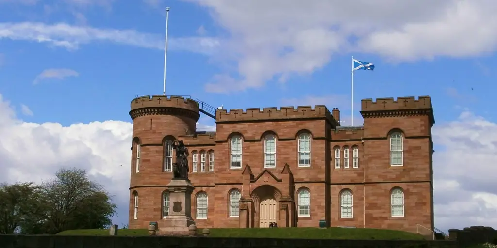 The front of Inverness Castle with a circular battlement on the left side and a Scottish flag flying above it