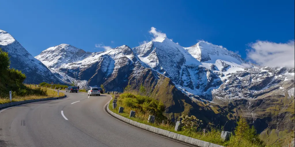 A car driving on the Grossglockner High Alpine Road, Austria with snowy peaks in the distance 