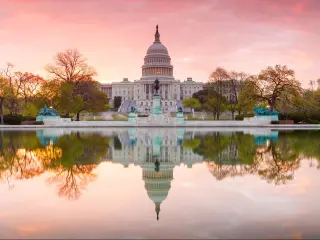 Washington DC, USA with a panorama view of The United States Capitol building taken at sunrise and reflecting in the lake in the foreground.