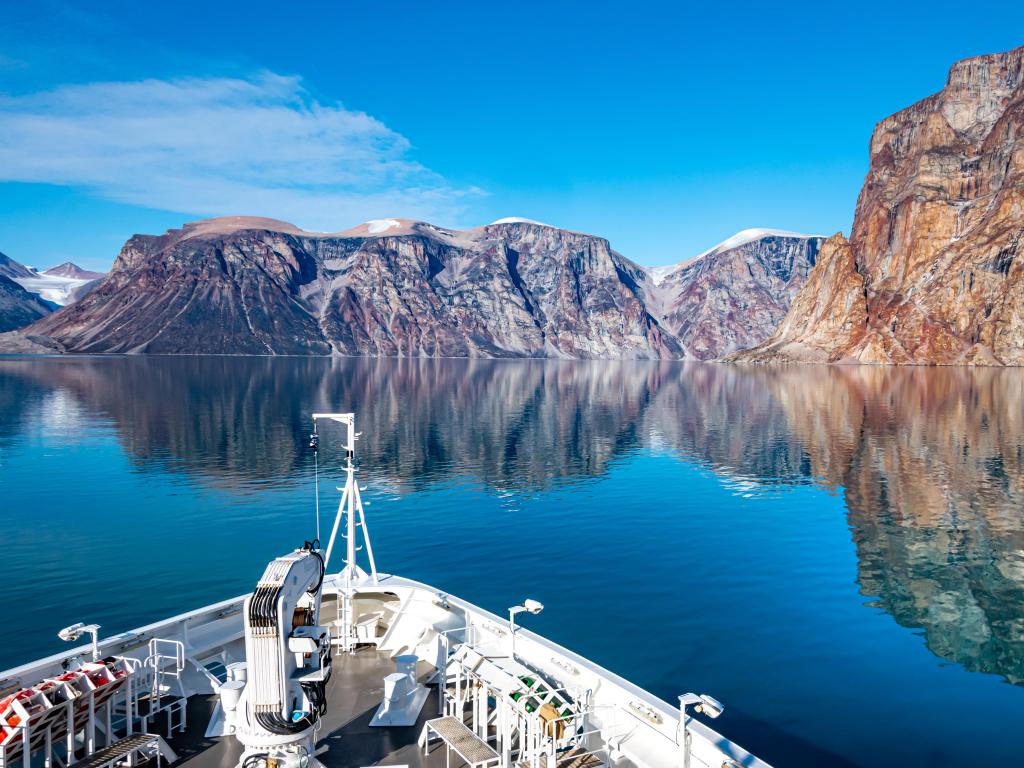 A boat arriving through San Fjord in Nunavut, Canada, with a clear blue sky above