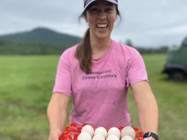 A woman holding a tray of eggs in a field