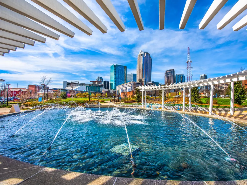 Charlotte, North Carolina, USA with a view of the city skyline from First Ward Park Fountain on a sunny day.