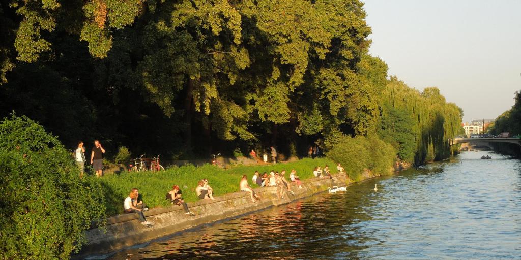 People sit on the banks of the Landwehr Canal in Berlin enjoying the sunshine and feeding ducks