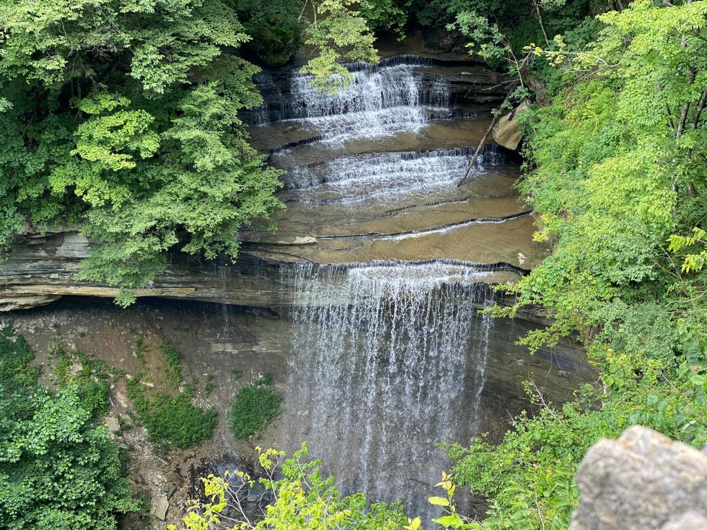 Beautiful waterfall with a stone  base, surrounded by lush greenery