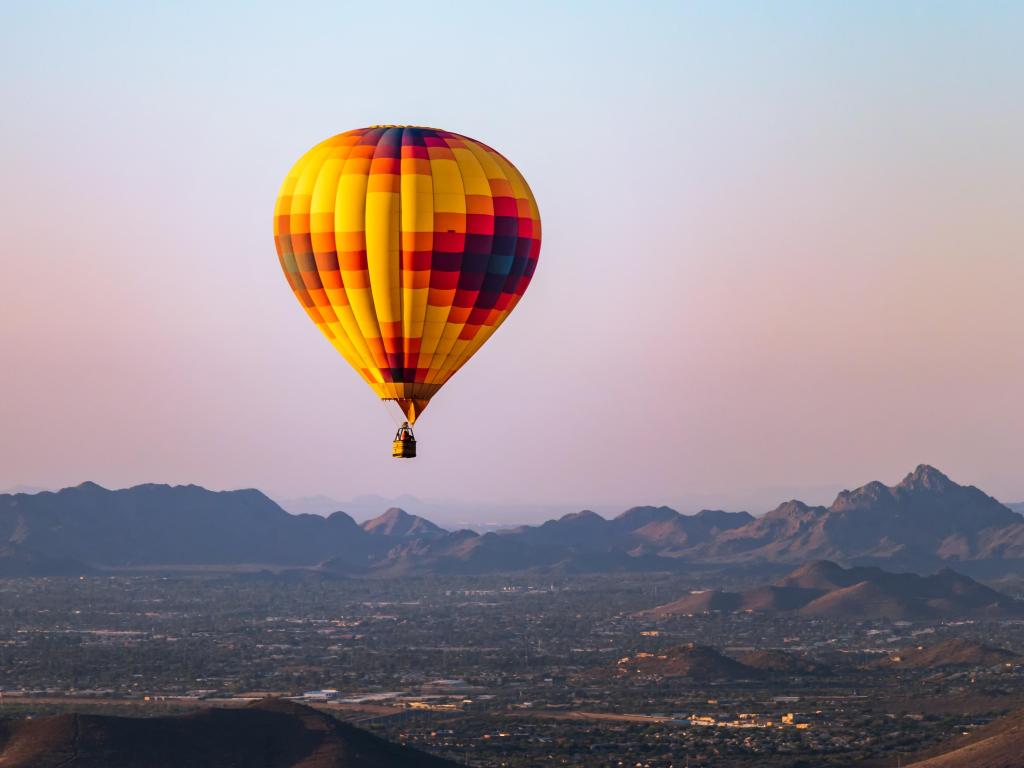 A hot air balloon flies over Phoenix Arizona with the Sonoran Desert in the background.