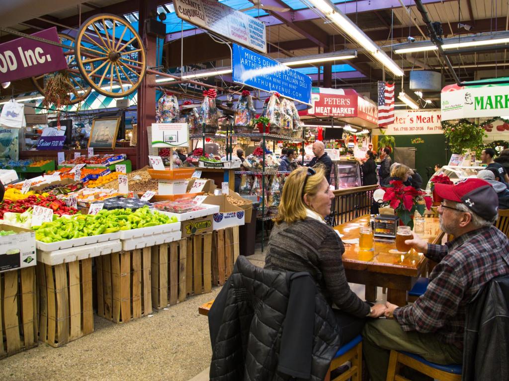 People sitting at a table in an indoor food market at Arthur Avenue, Bronx, New York
