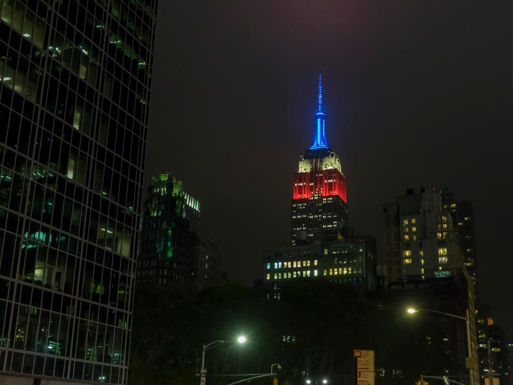 Evening view of Empire State Building lit at the top in red, white and blue to recognize the events of 9/11