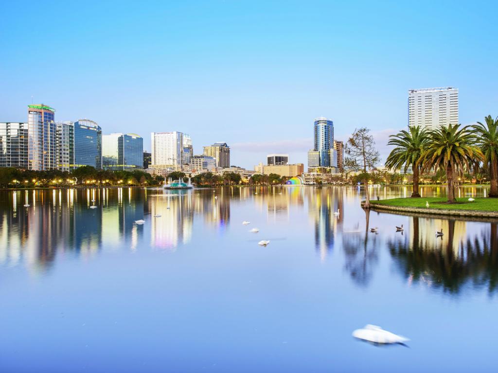 Orlando, Florida, USA with the downtown skyline panorama over Lake Eola with urban skyscrapers, tropic palm trees and clear sky.