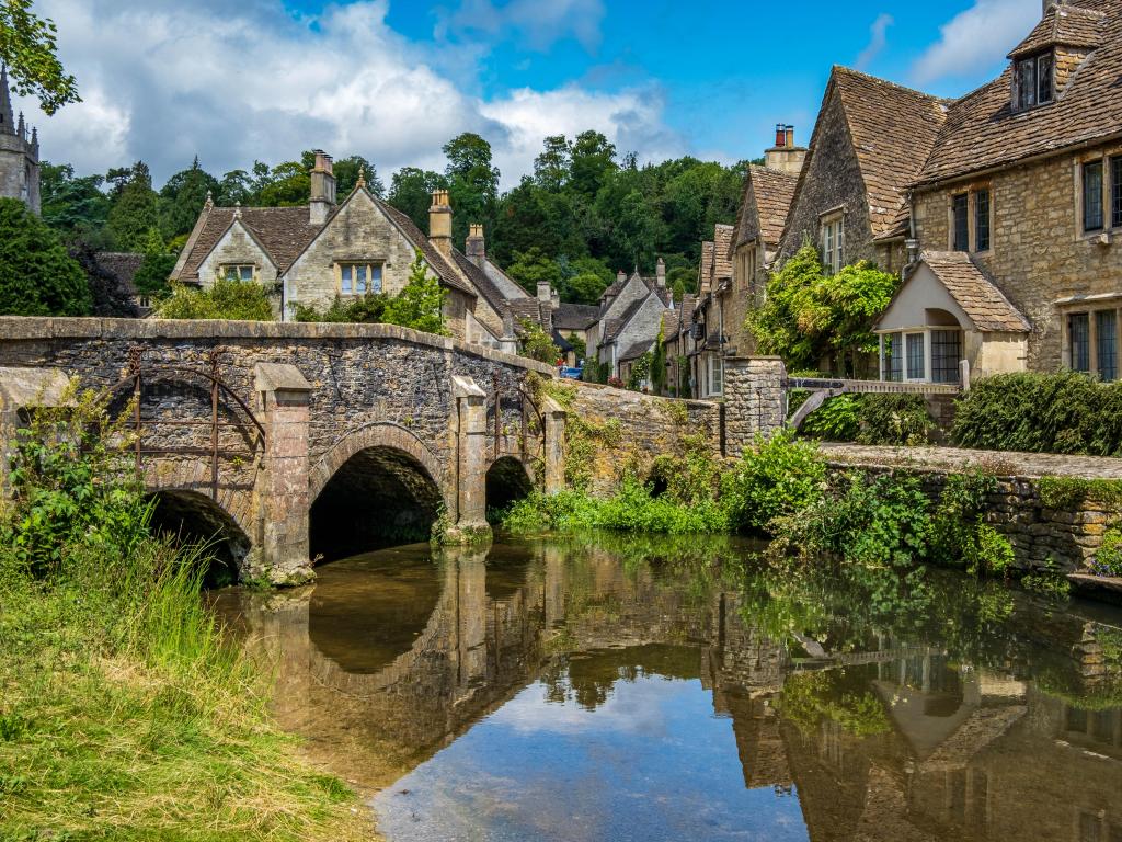 Cotswolds, UK with blue skies and reflections in the picturesque Cotswold village of Castle Combe.