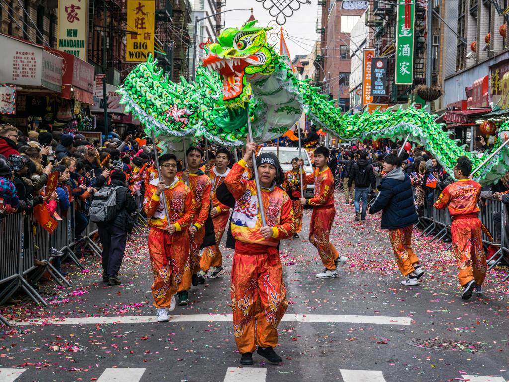 Lunar New Year Parade in Chinatown celebrating the Chinese New Year, with people lining streets and large bright green paper dragons paraded