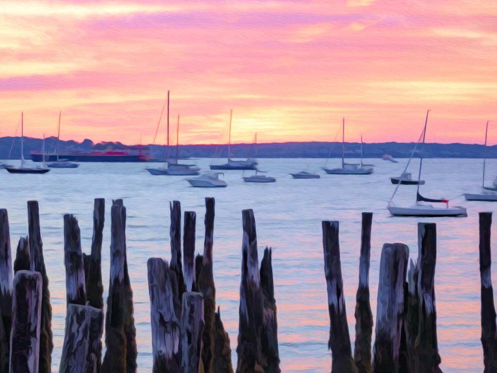 Waterfront view of pleasure boats and freighter beyond rotting wharf pilings in Portland, Maine, USA, at sunrise, with digital oil-painting effect, for coastal, nautical, and travel themes