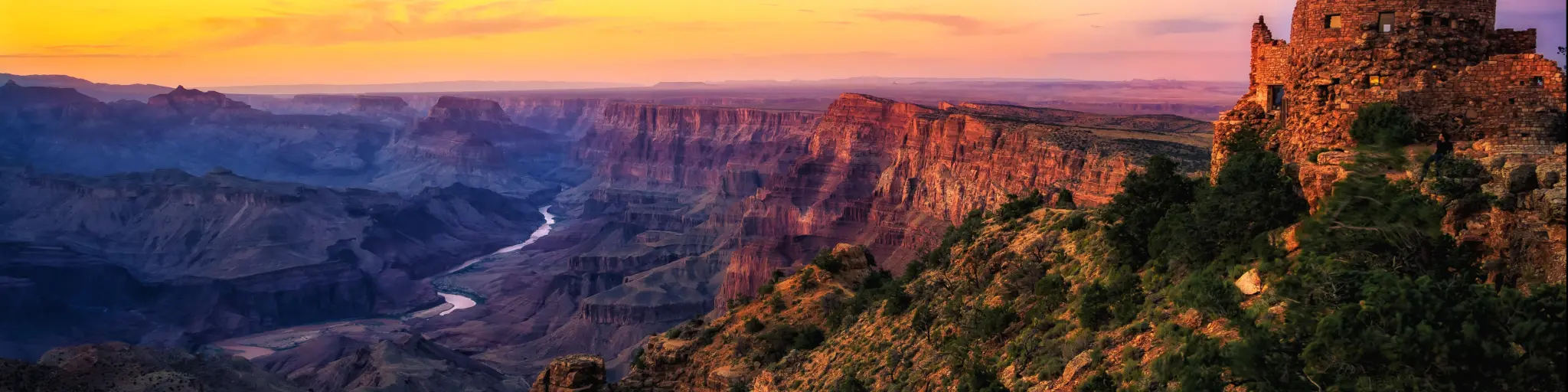Grand Canyon, Grand Canyon National Park, Arizona with the Watchtower in the foreground at sunset overlooking the great valley, rocks and river below.