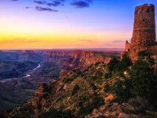 Grand Canyon, Grand Canyon National Park, Arizona with the Watchtower in the foreground at sunset overlooking the great valley, rocks and river below.