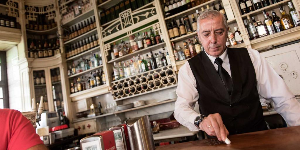 A barman at Seville's El Rinconcillo writes someone's order on the wooden  bar in chalk