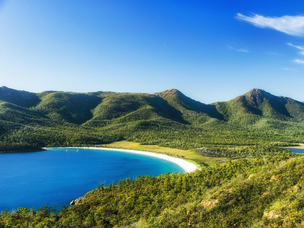 Tasmania, Australia on a clear day, with mountains in the background and a calm sea in a bay in the foreground. 