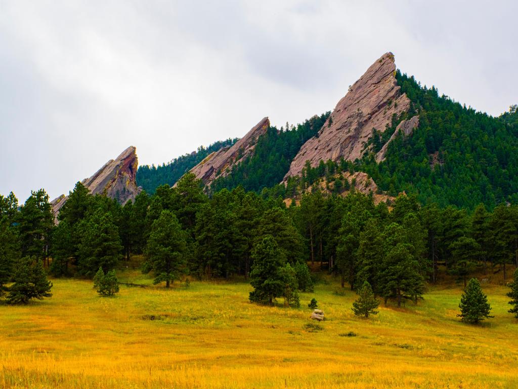 beautiful image of the Flatirons dark granite mountains from below with green and yellow lawns, in Chautauqua Park in Boulder Colorado