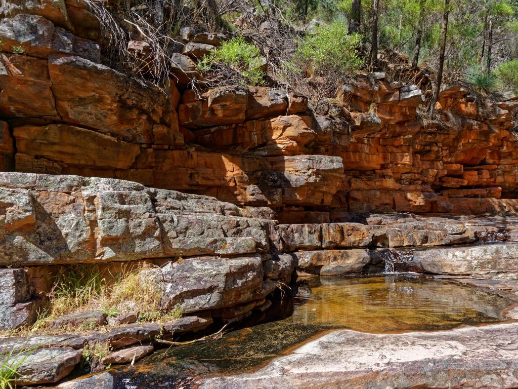 Mount Remarkable National Park, South Australia with a view of the Creek Trail at Narrow Gorge, a small waterfall and trees on the rocks.