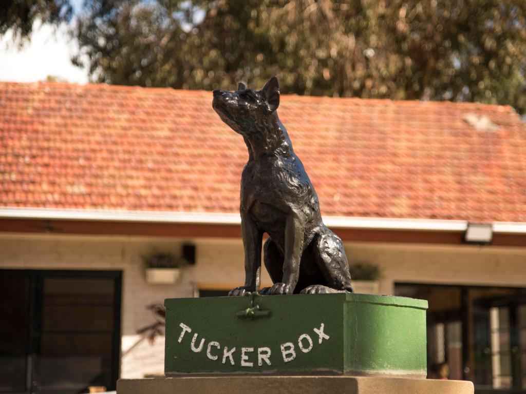 Quirky historical statue of a dog sitting on a Tuckerbox