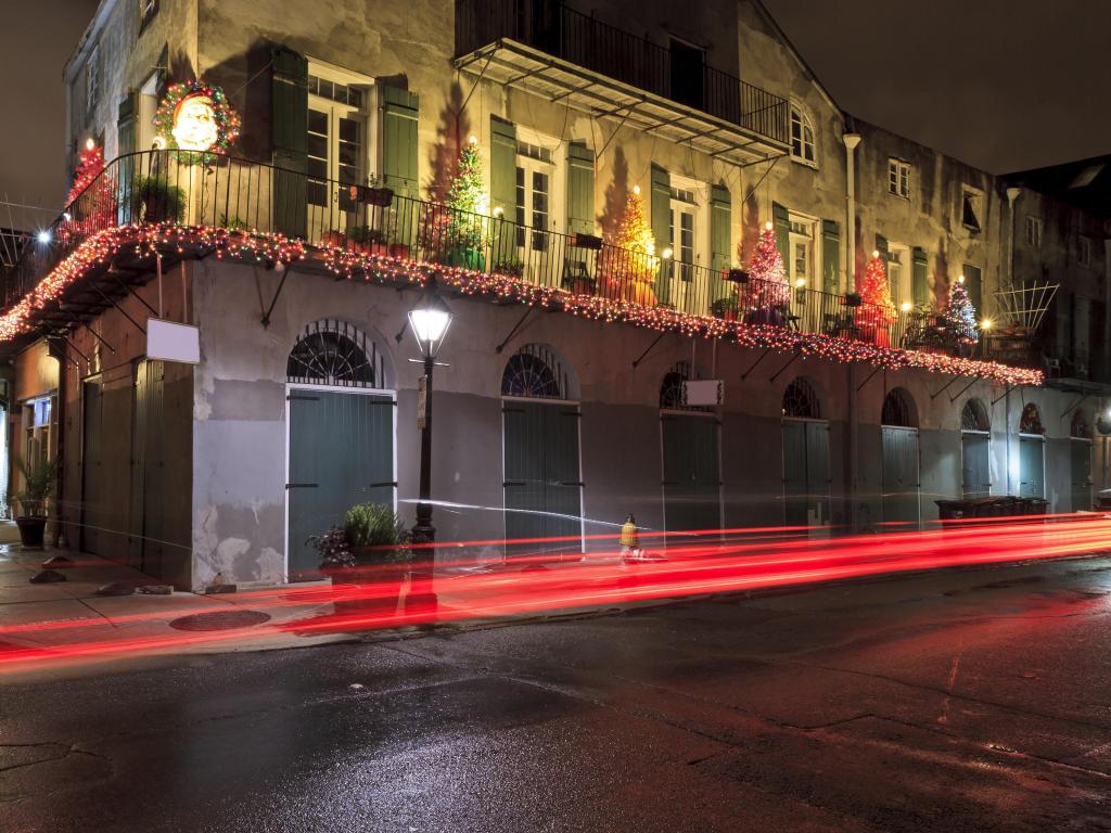 Holiday decorations in New Orleans' French Quarter at night, with taillights streaking by