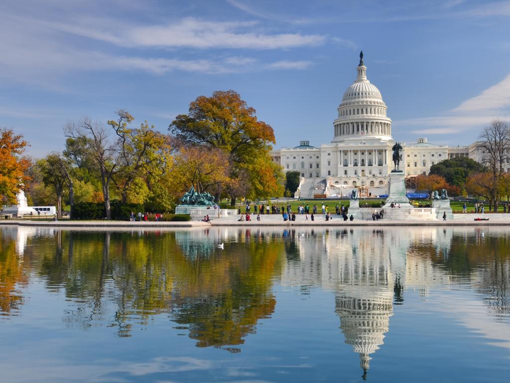 Washington DC, USA with the US Capitol Building in Autumn in the background reflected in the water in the foreground.