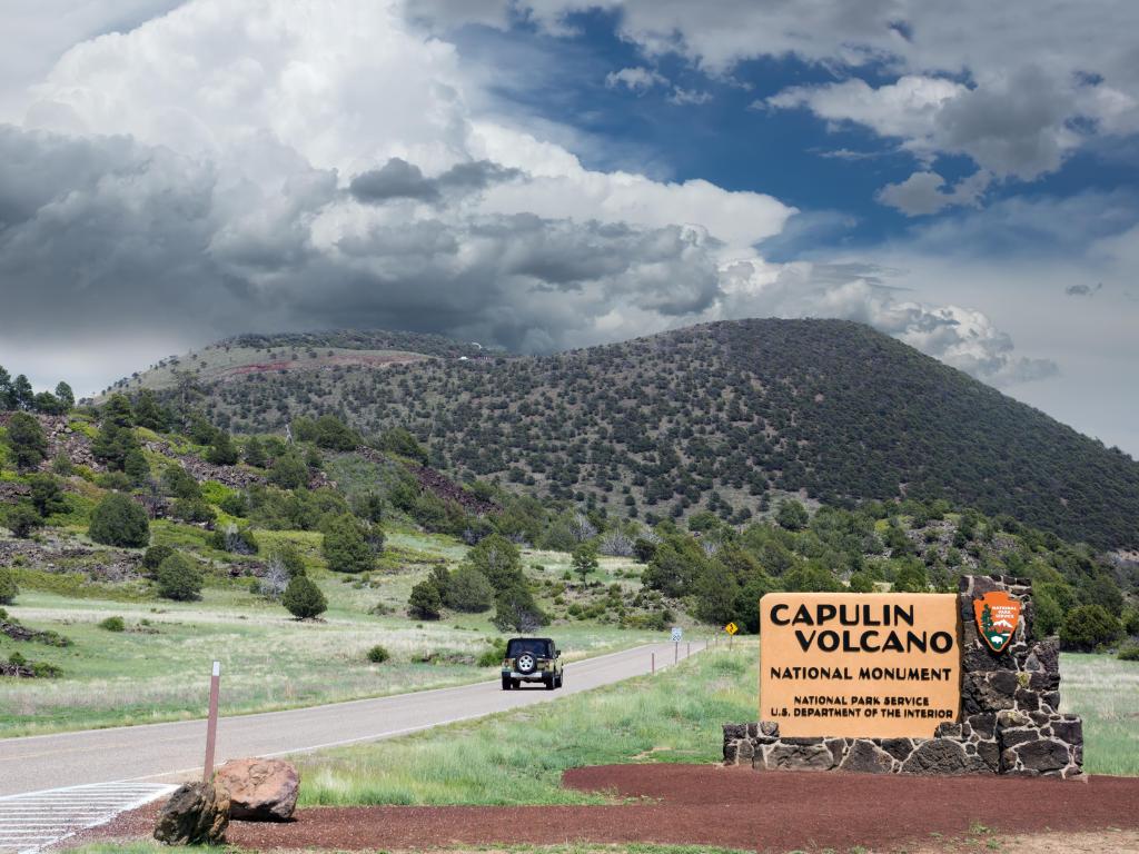 The entrance sign and the volcano in the background on a cloudy day