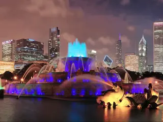 A panoramic view of night-lit and skyscrapers of Chicago with Buckingham fountain in Grant Park at the front
