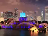 A panoramic view of night-lit and skyscrapers of Chicago with Buckingham fountain in Grant Park at the front