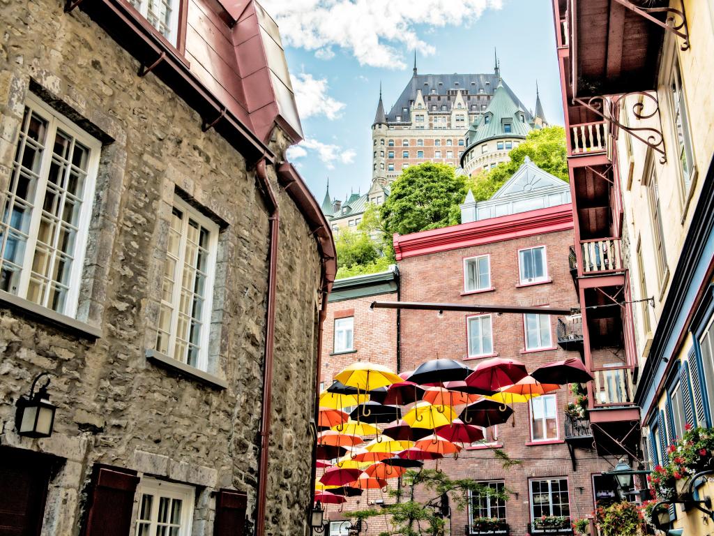 Quebec city, Canada a typical street in with umbrellas hanging from the buildings and the grand building in the background taken on a sunny day. 