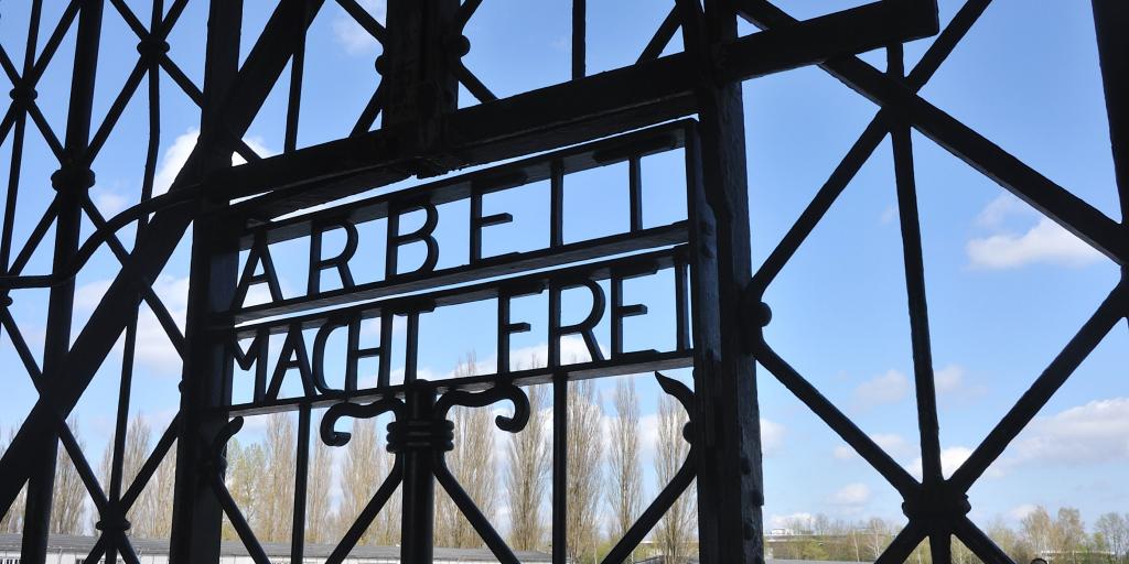 Close up of the words Arbeit Macht Frei on the gates of Dachau Concentration Camp, Munich, Germany, with blue sky visible beyond them