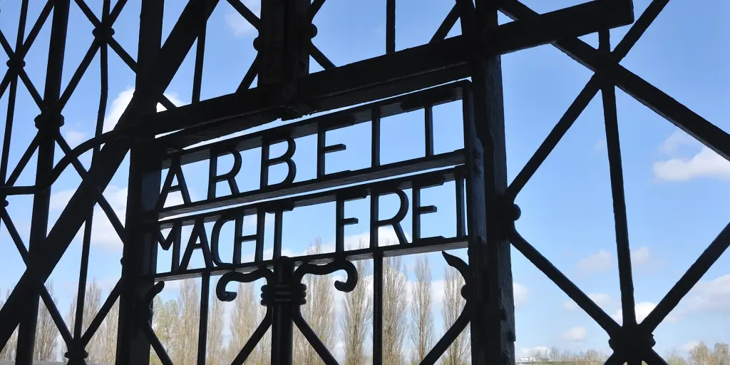 Close up of the words Arbeit Macht Frei on the gates of Dachau Concentration Camp, Munich, Germany, with blue sky visible beyond them