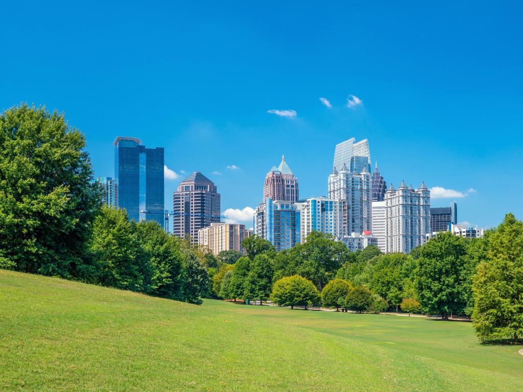 Atlanta, USA with the midtown city skyline in the background and the stunning green park in the foreground with trees separating the two on a sunny day. 