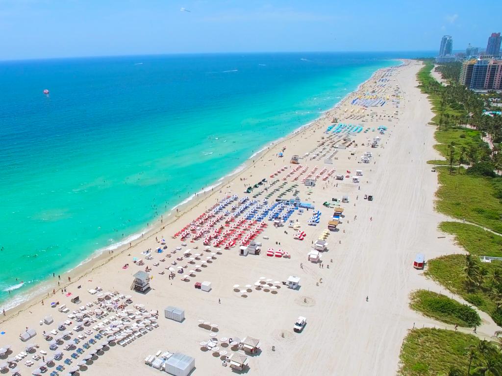 South beach in Miami stretching into the distance with sun loungers everywhere and crystal clear waters.