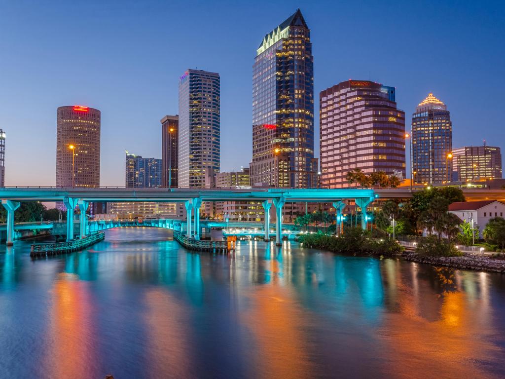 Tampa, Florida, USA with the downtown city at night, the bridge lit up and Hillsborough River in the foreground.