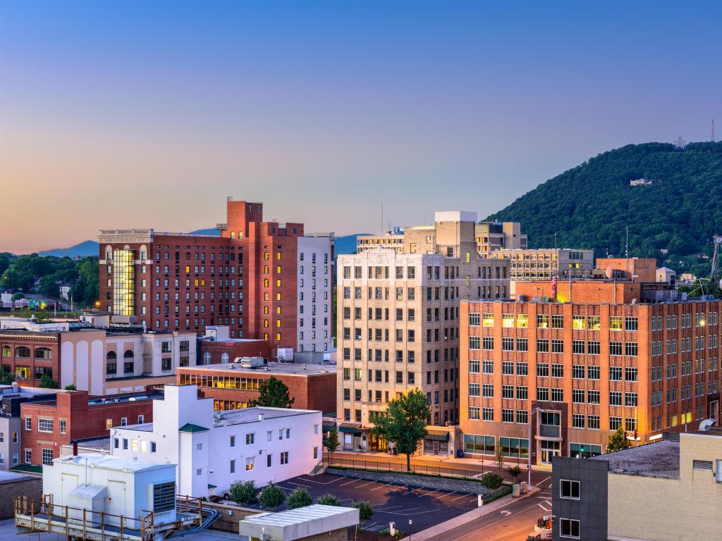 Roanoke, Virginia, USA downtown skyline with a tree-lined mountain in the distance taken at early evening.