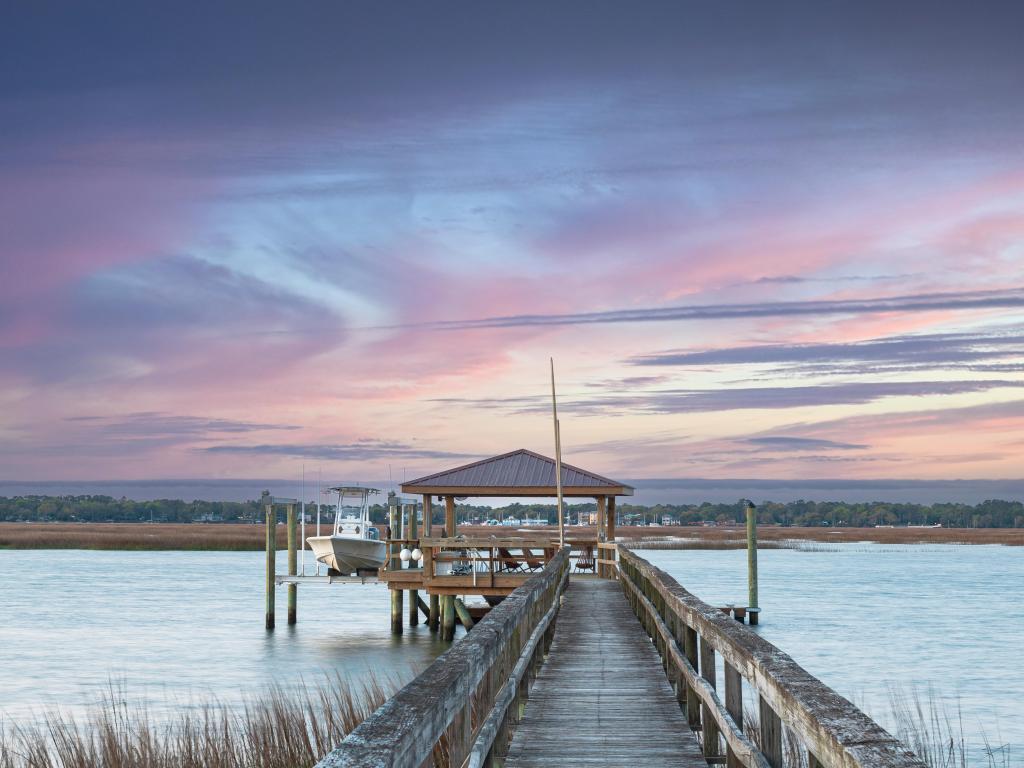 Dockside view of boathouse walking on dock with pink sky in Beaufort, South Carolina.