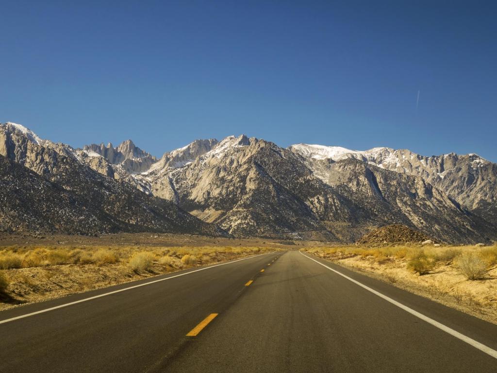 The iconic California State Highway 395 in Owens Valley on Eastern Flanks of Sierra Nevada Mountains with distant Mount Whitney on Horizon.