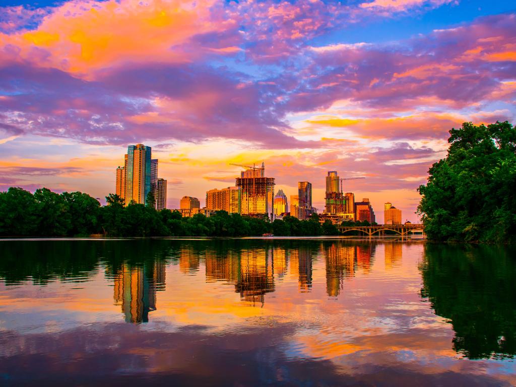  An awe-inspiring, dramatic sunset in Austin, Texas casts a mirror image over Town Lake, with an extraordinary display of colorful clouds reflecting on the serene, glass-like surface of the Colorado River.